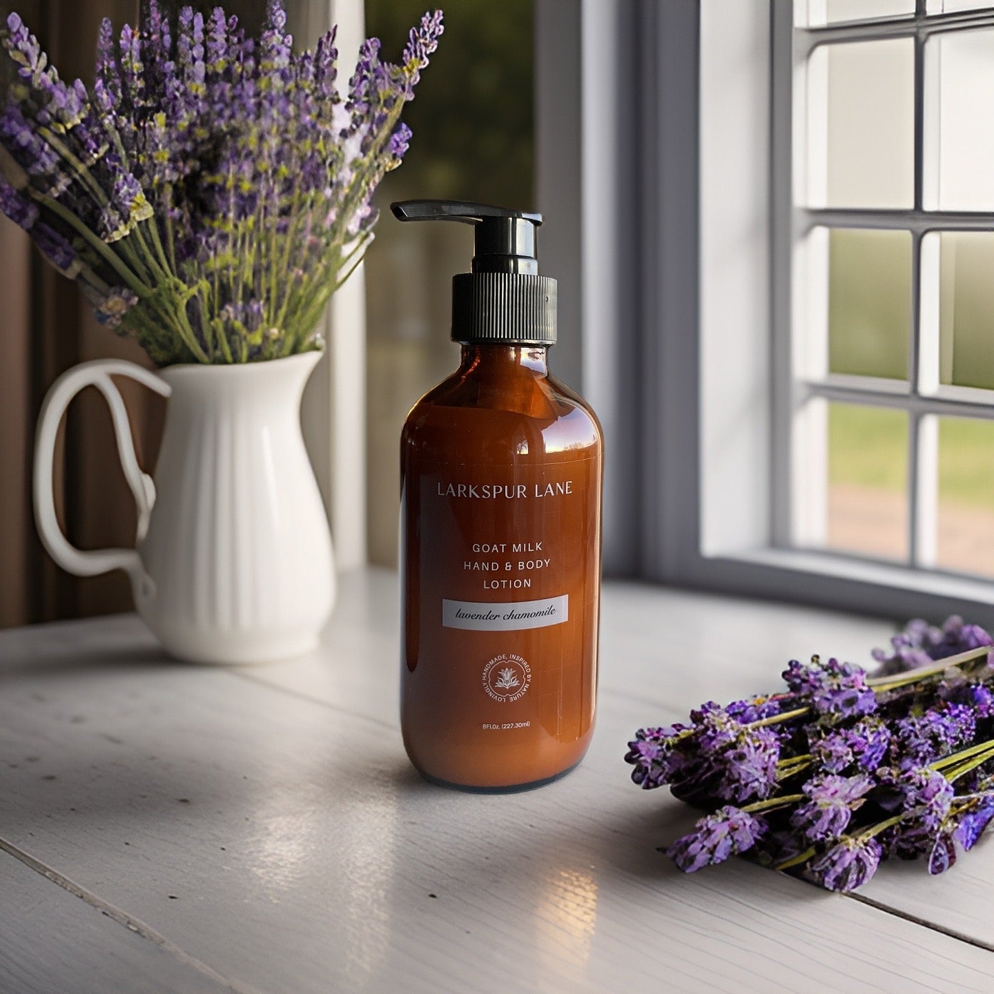 a glass bottle of goats milk lotion sitting on a counter; Larkspur Lane