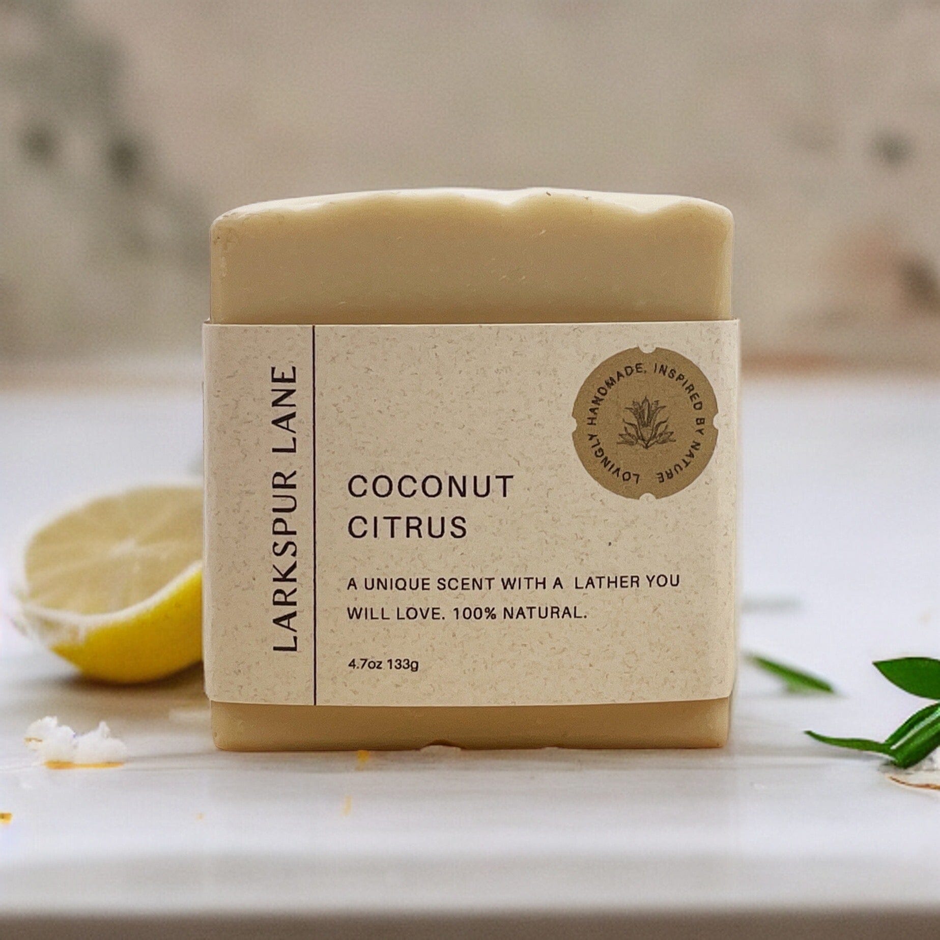 Larkspur Lane’s Coconut Citrus Soap sitting on a counter with citrus and coconut 