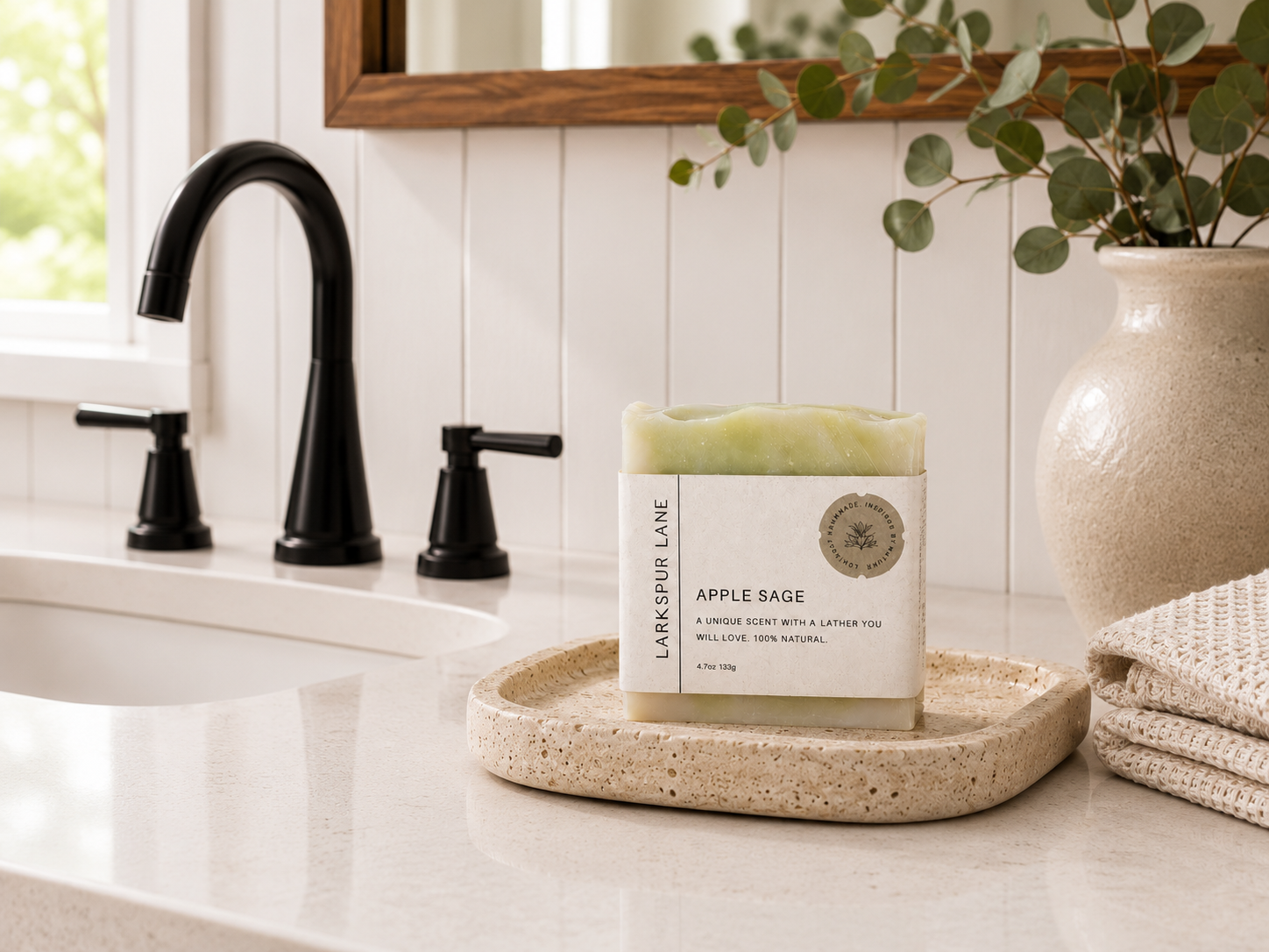 Larkspur Lane Apple Sage handcrafted soap displayed on a stone soap dish in a bright modern farmhouse bathroom.