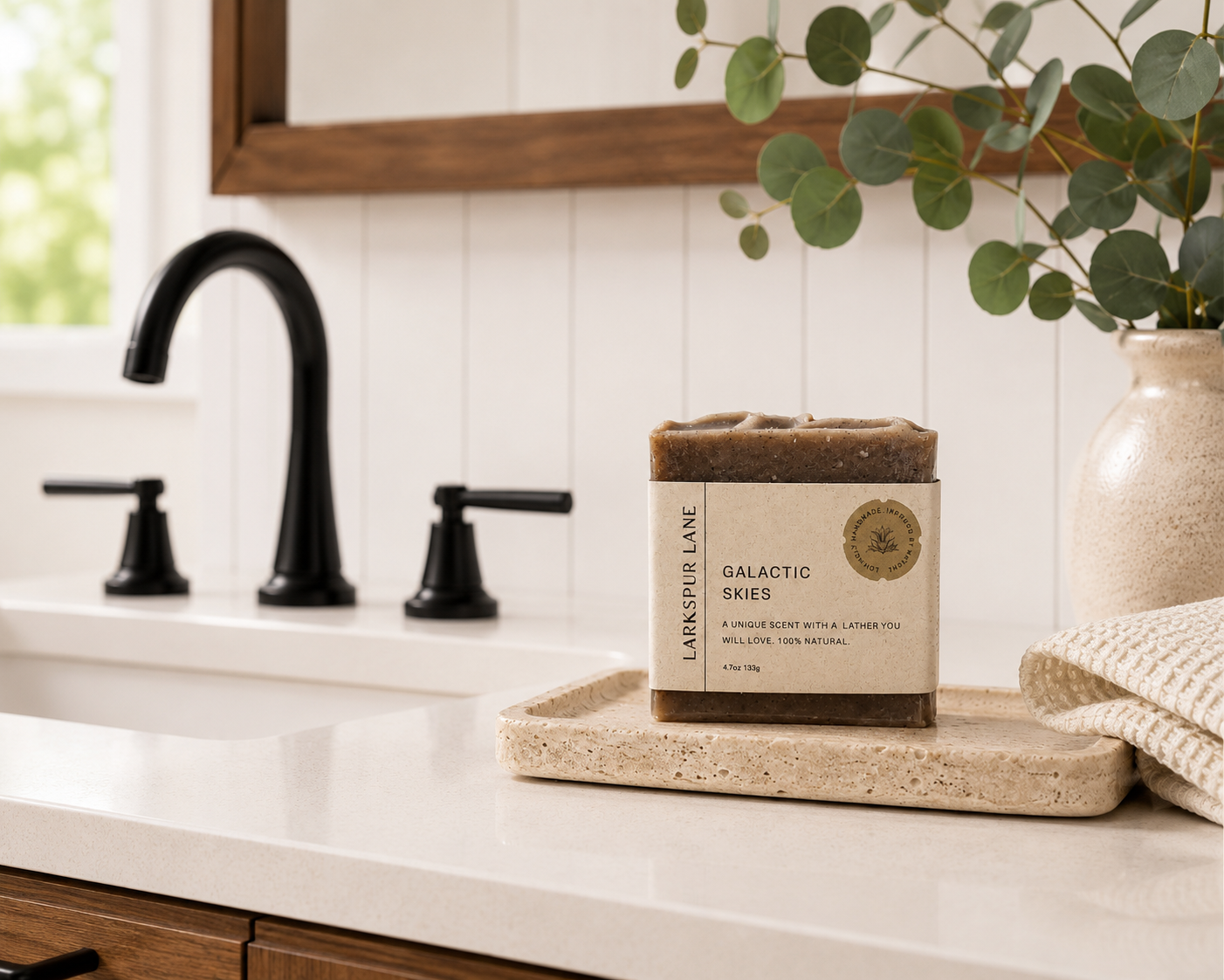 Larkspur Lane Galactic Skies handcrafted soap displayed on a stone soap dish in a bright modern farmhouse bathroom.