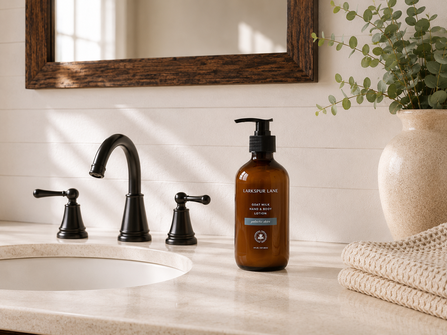 Galactic Skies Goat Milk Hand & Body Lotion by Larkspur Lane in an amber glass pump bottle on a bright modern farmhouse bathroom vanity.