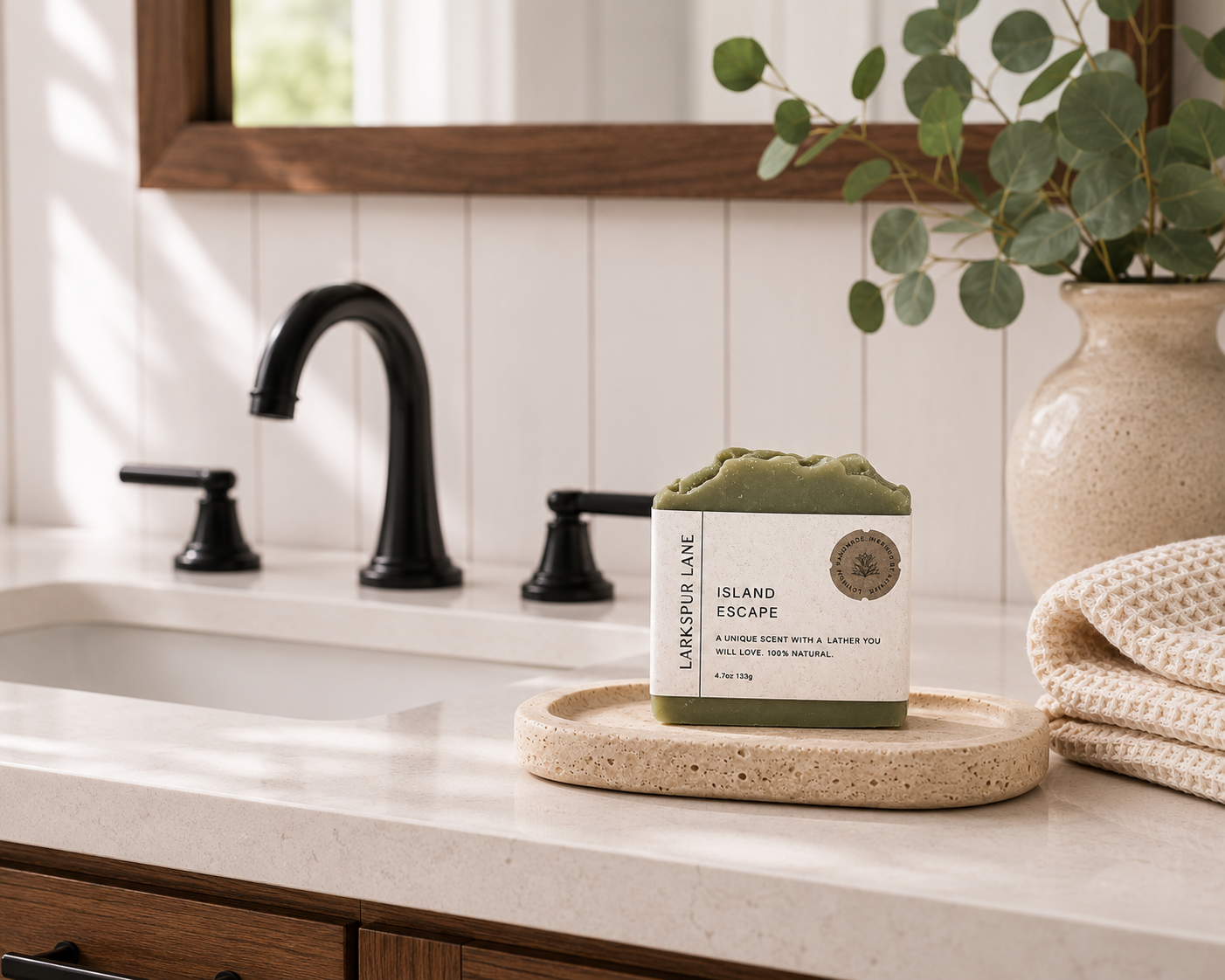 Larkspur Lane Island Escape handcrafted soap displayed on a stone soap dish in a bright modern farmhouse bathroom.