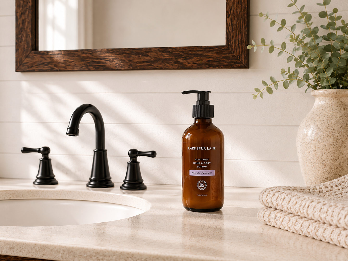 Lavender Chamomile Goat Milk Hand & Body Lotion by Larkspur Lane in an amber glass pump bottle on a bright modern farmhouse bathroom vanity.