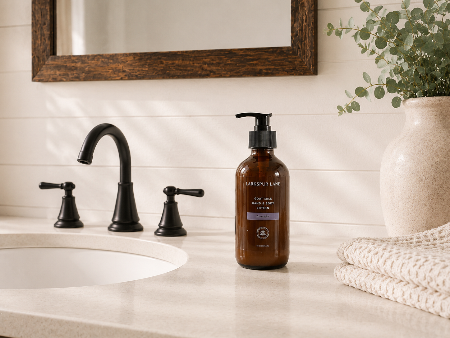 Lavender Goat Milk Hand & Body Lotion by Larkspur Lane in an amber glass pump bottle on a bright modern farmhouse bathroom vanity.