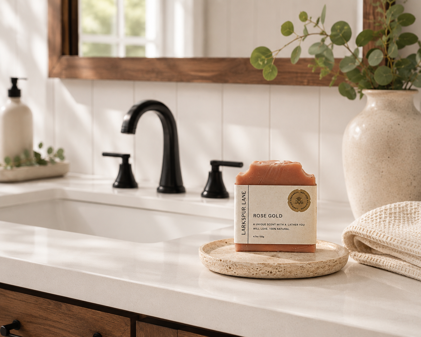 Larkspur Lane Rose Gold handcrafted soap displayed on a stone soap dish in a bright modern farmhouse bathroom.