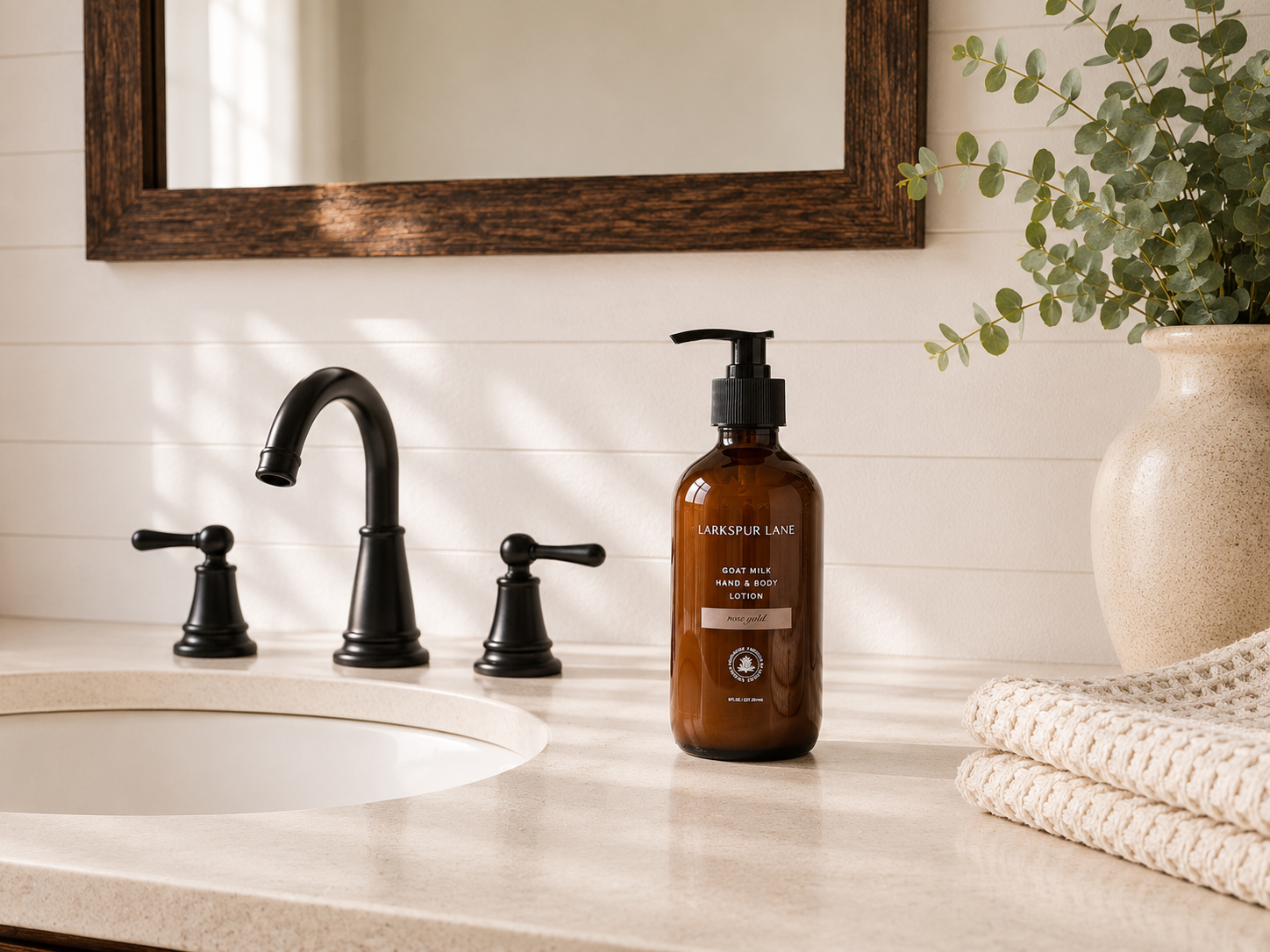 Rose Gold Goat Milk Hand & Body Lotion by Larkspur Lane in an amber glass pump bottle on a bright modern farmhouse bathroom vanity.