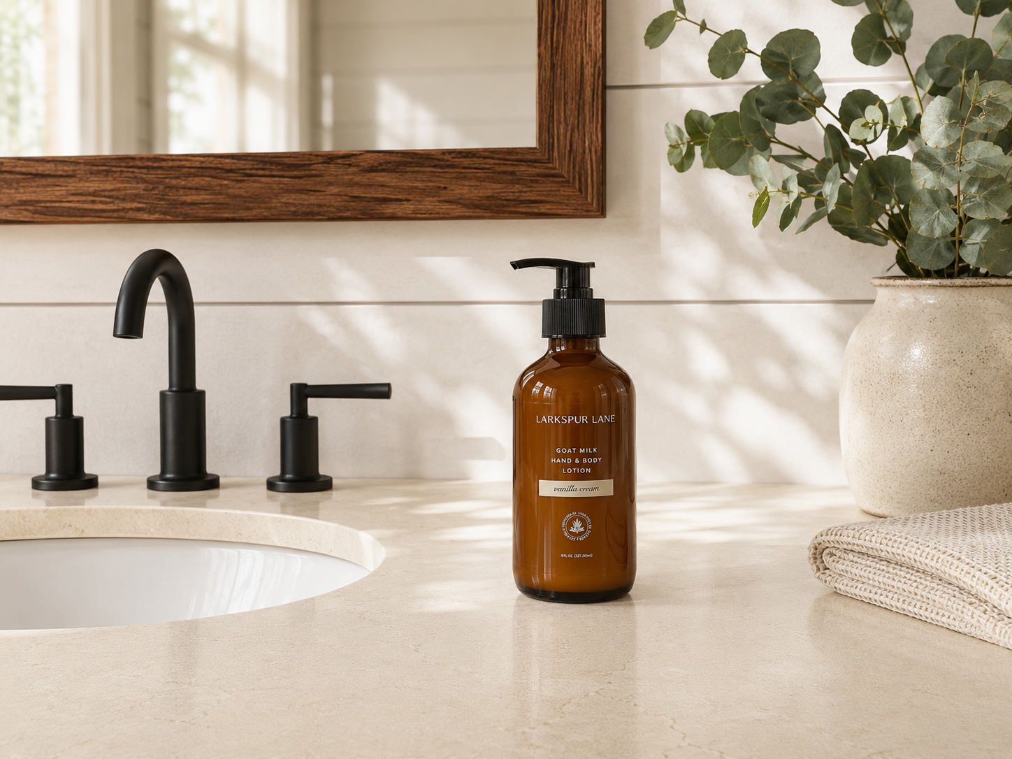 Vanilla Cream Goat Milk Hand & Body Lotion by Larkspur Lane in an amber glass pump bottle on a bright modern farmhouse bathroom vanity.