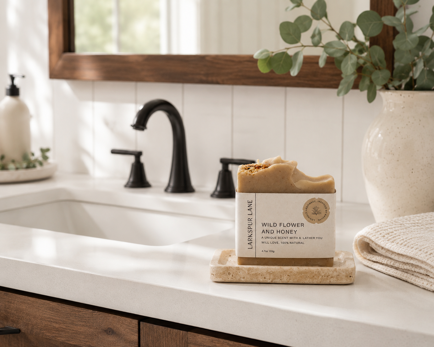 Larkspur Lane [Wild Flower & Honey Soap handcrafted soap displayed on a stone soap dish in a bright modern farmhouse bathroom.